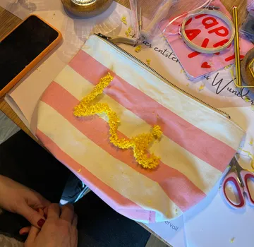 Gestreifte Tasche mit gelber Stickerei, Bastelbedarf daneben.