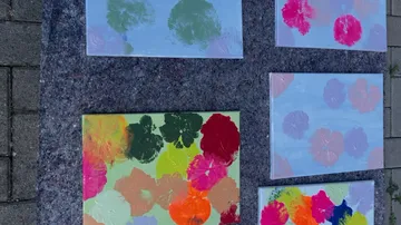 Fünf bunte Blumenbilder auf dem Pflaster.