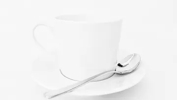 Weiße Tasse und Untertasse mit Löffel.
