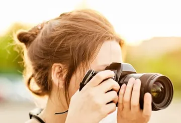 Person fotografiert mit Kamera im Freien.