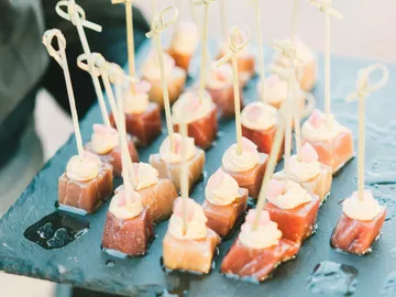 Appetizers on black stone, served with skewers.