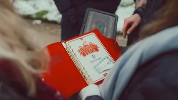 People holding a festive mission folder outdoors.