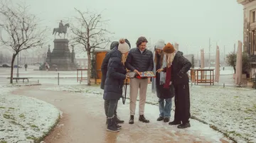 Gruppe betrachtet Buch im verschneiten Park.
