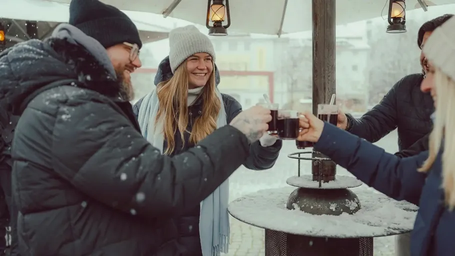 Gruppe stößt mit heißen Getränken im Schnee an.