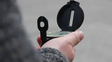 Hand hält einen Kompass im Freien.
