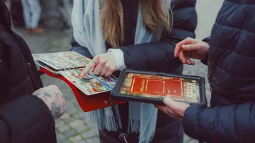 Personen nutzen Tablets und bunte Karten draußen.