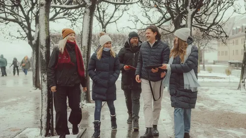 Group walking in snowy park with trees.