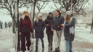 Group walking on snowy path with trees.