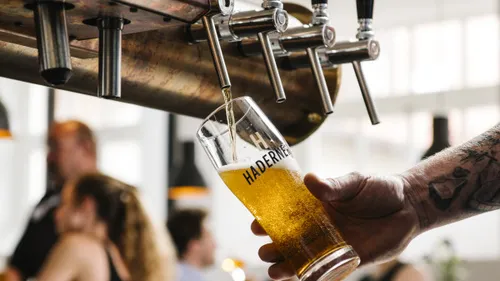 Person gießt Bier aus einem Zapfhahn.
