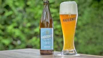 Bierflasche und Glas auf Holztisch im Freien.