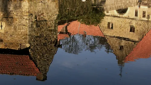 Gebäudespiegelung in ruhigem Wasser.