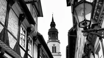 Church tower rising between narrow buildings.