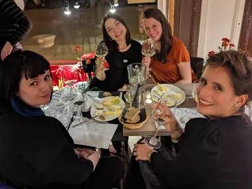 Four women enjoy dinner and drinks together.