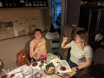 Two women drink red wine in a cozy restaurant.