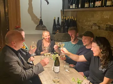 Group of people raise glasses in a cozy wine cellar.