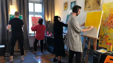 Vier Personen malen auf Leinwand in einem Raum.