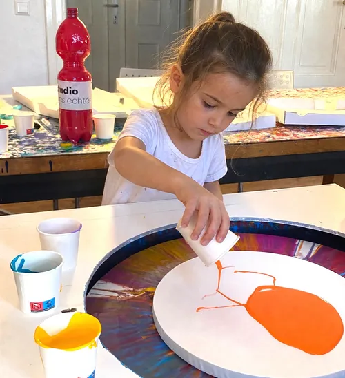 Kind gießt Farbe im Kunststudio.