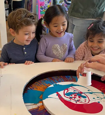 Kinder beobachten bunte Spinkunst.