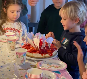 Kinder am Tisch mit Geburtstagskuchen.