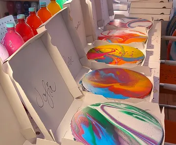 Colorful pizzas in boxes on a counter.
