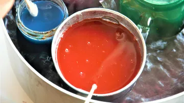 Buckets of red and blue paint in workshop.