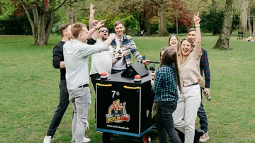 Gruppe feiert am Getränkewagen im Park.