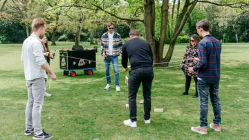 Gruppe spielt Outdoor-Spiel mit Blöcken auf Rasen.
