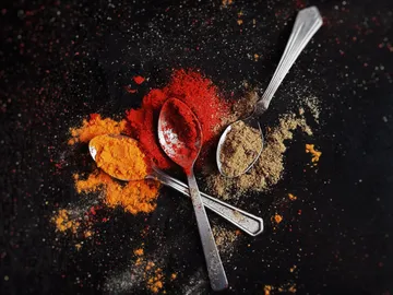 Spread the spoon with spices on a dark surface.
