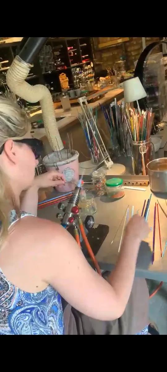 Person erstellt Glaskunst an einem Arbeitsplatz.