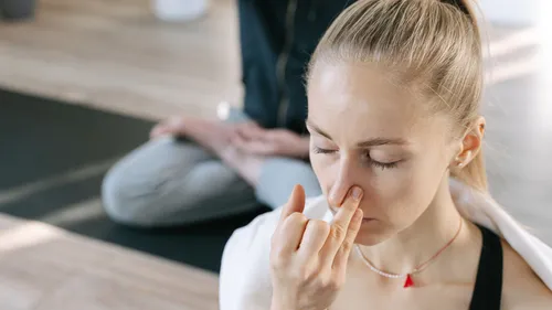 Frau übt Yoga-Atemübungen drinnen.