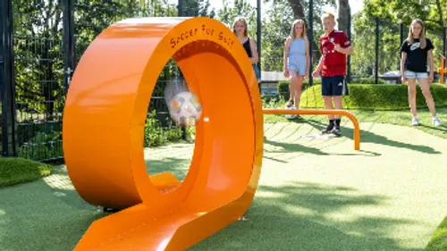 Fußball durch orangene Schleife, Parkumgebung.