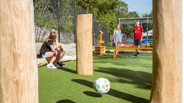 Kinder spielen Fußball auf einem Spielplatz.