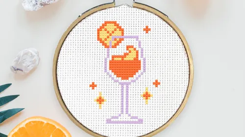Kreuzstich-Cocktailrahmen mit Orangenscheibe.