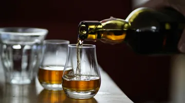 Whiskey wird in Glas auf Tisch gegossen.