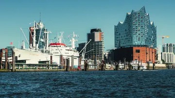 Schiff liegt in moderner Hafenumgebung.