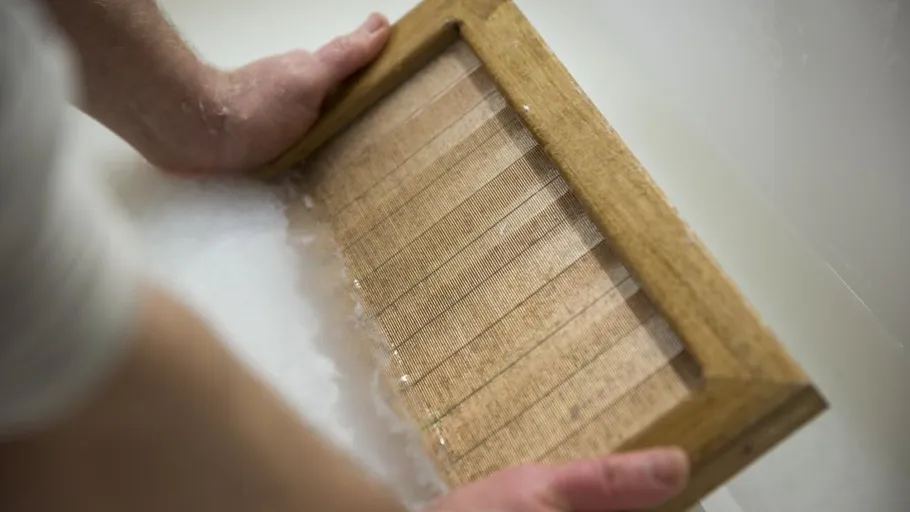 Hands making paper with wooden frame.