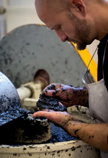 Man handling wet clay in workshop.