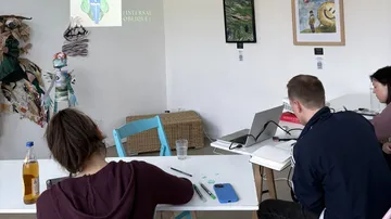 People sit, work at a table in a room.