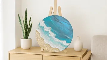 Round painting depicts ocean on easel.