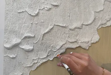 Hand applying texture on canvas surface.