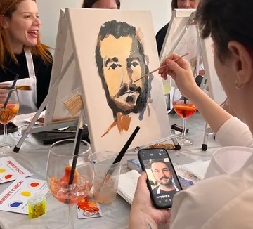 Person malt Porträt bei Kunstkurs-Tisch.