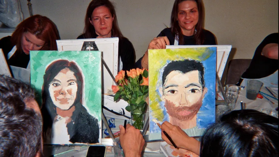 People painting portraits at a table.
