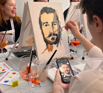 Person painting portrait at social gathering.