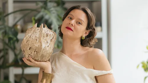 Frau hält eine skulpturale Vase drinnen.