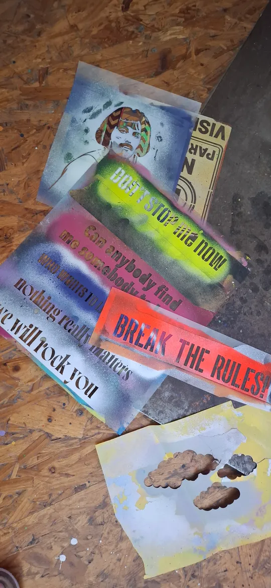 Bunte Schablonen mit Text auf Holzboden.