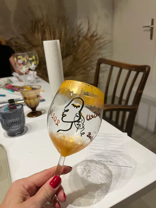 Hand holds painted wine glass indoors.