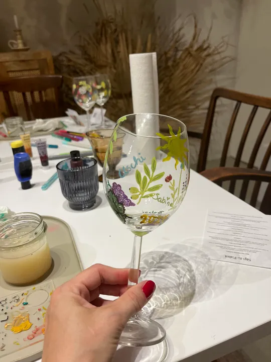 Hand holding decorated wine glass indoors.