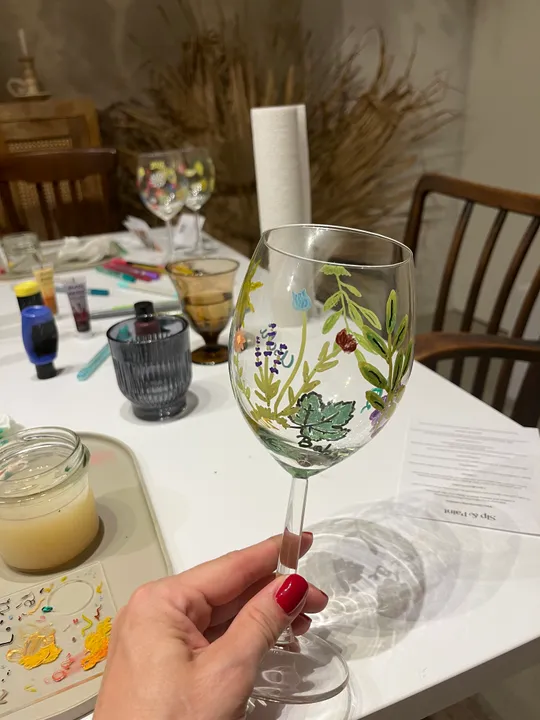 Hand holds painted wine glass indoors.