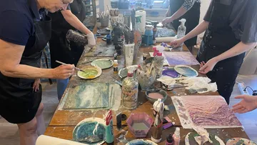 Personen malen an einem Workshop-Tisch.