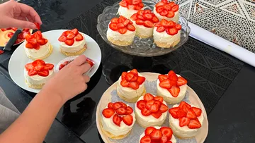 Hände platzieren Erdbeeren auf Mini-Käsekuchen.